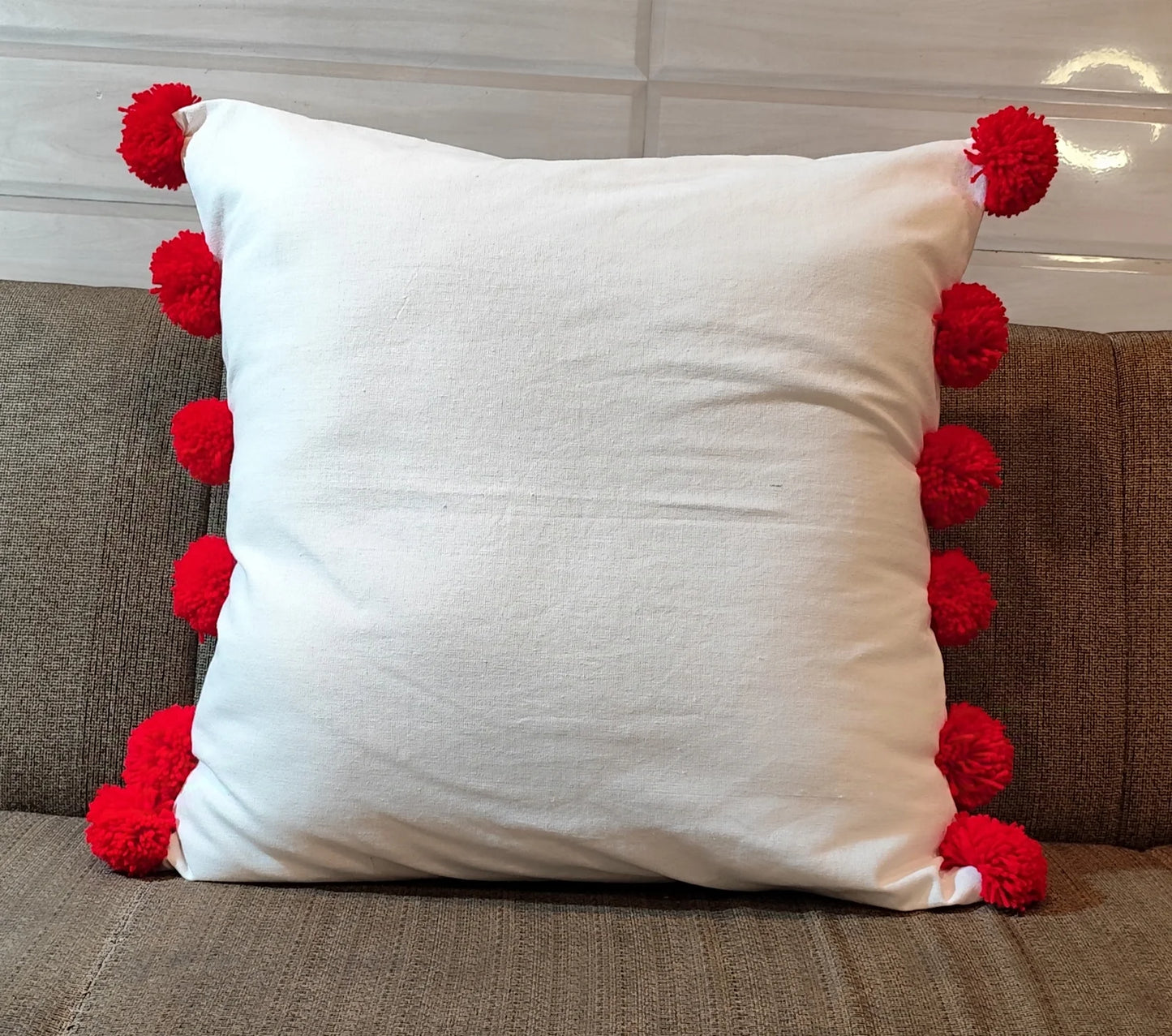 White cushion cover with red pompom balls